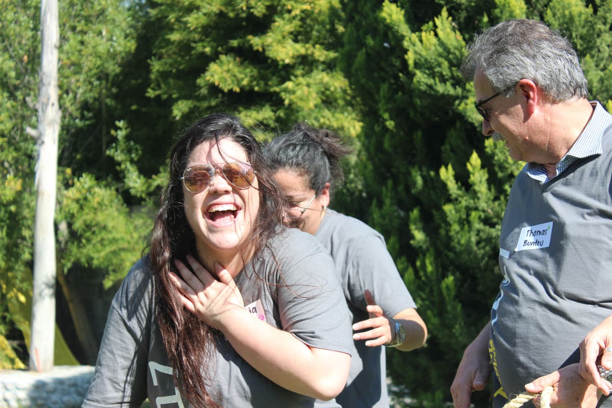 Colaboradores riendo mientras participan en un desafío dinámico, reflejando la diversión y la camaradería del rally empresarial