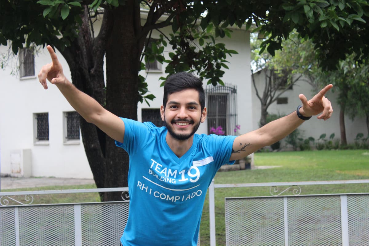 Colaborador con camiseta azul sonriendo mientras participa en el rally, reflejando entusiasmo y energía positiva