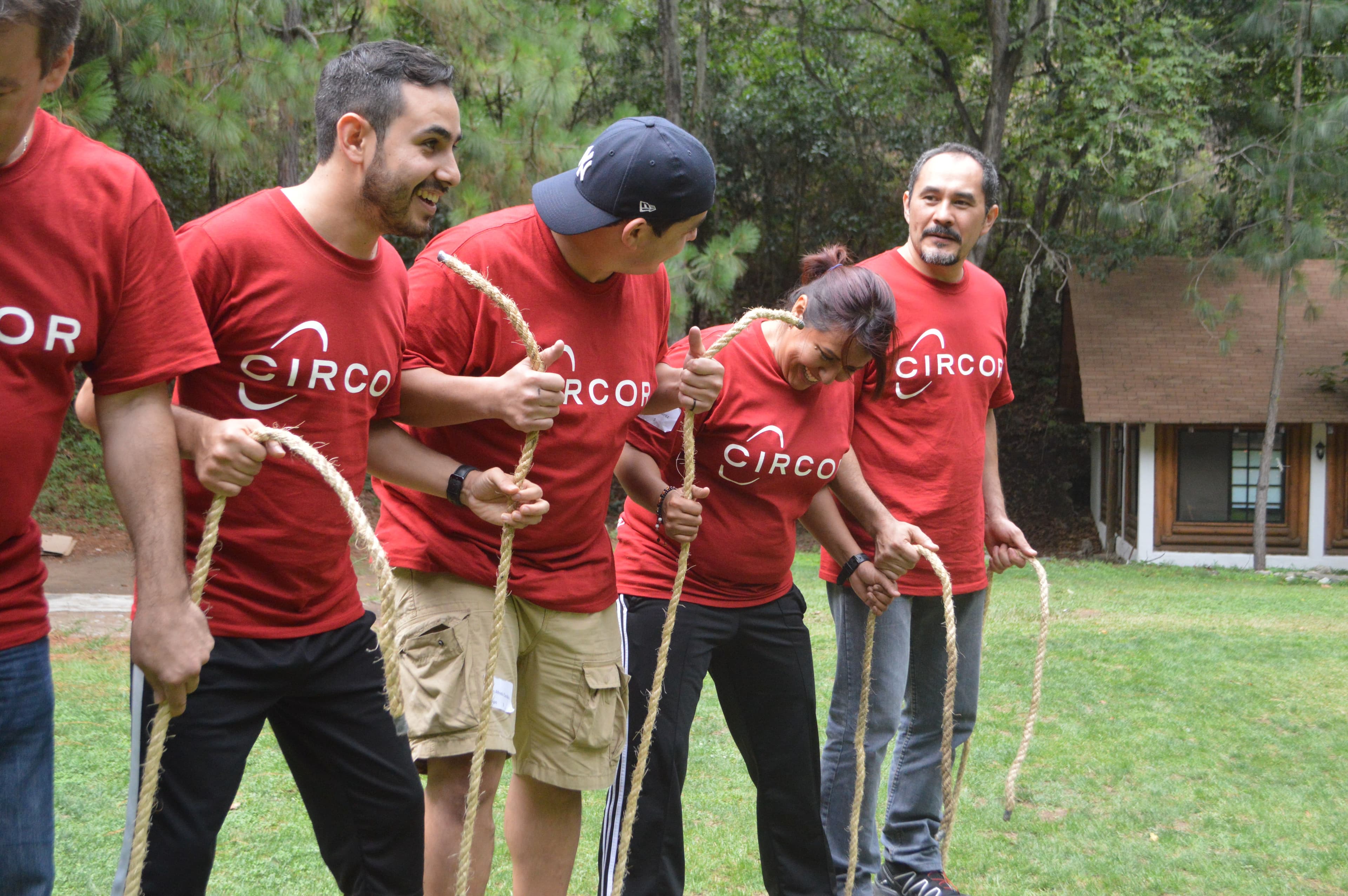 Grupo con camisetas rojas riendo mientras completan una actividad competitiva, destacando el trabajo en equipo