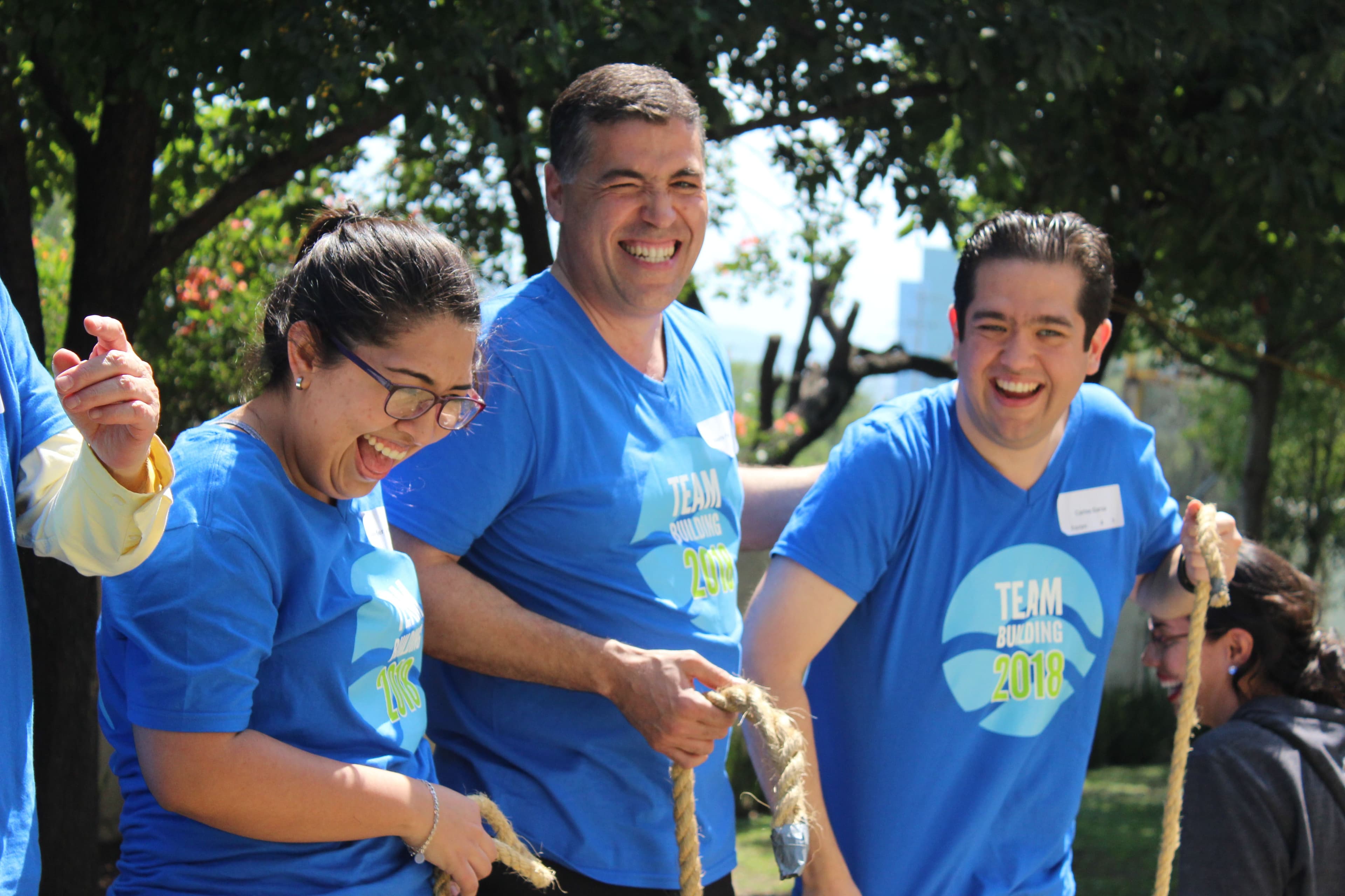 Hombre sonriendo ampliamente mientras ayuda a su equipo durante un desafío físico, reflejando el espíritu del rally empresarial
