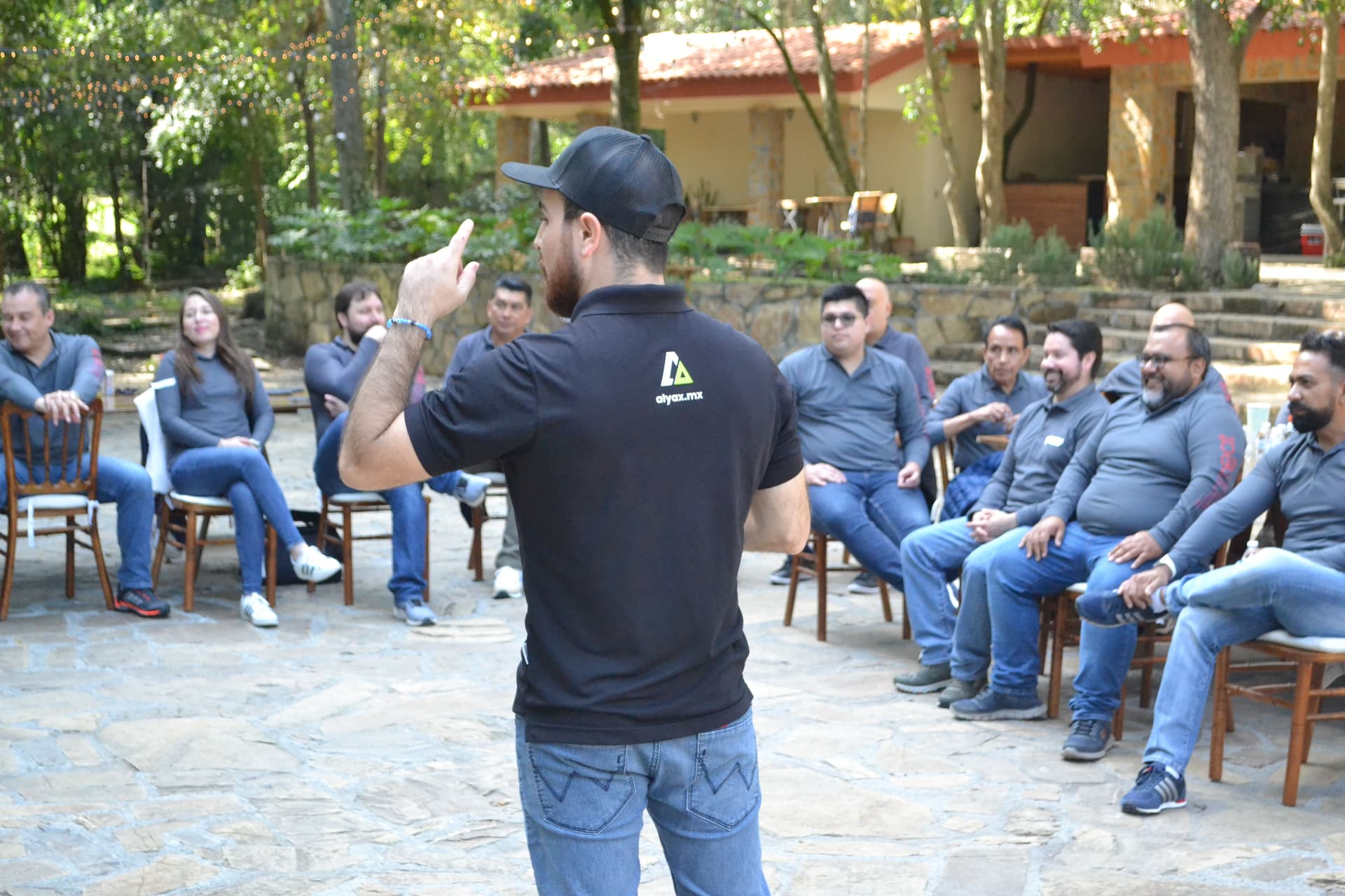 Participantes reunidos al aire libre en un círculo, escuchando instrucciones para una dinámica del rally empresarial